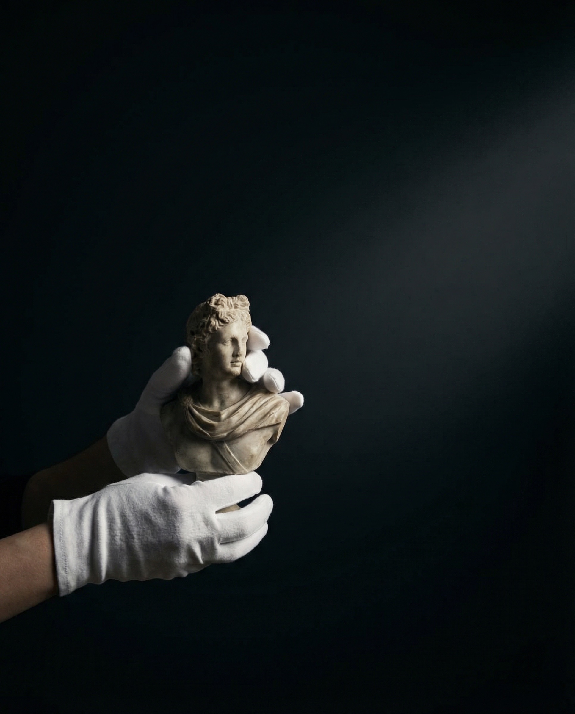 Mains gantées de blanc tenant un buste de marbre d'une déesse antique sur fond noir, protocole musée pour transport d'oeuvres d'art Griffon Movers