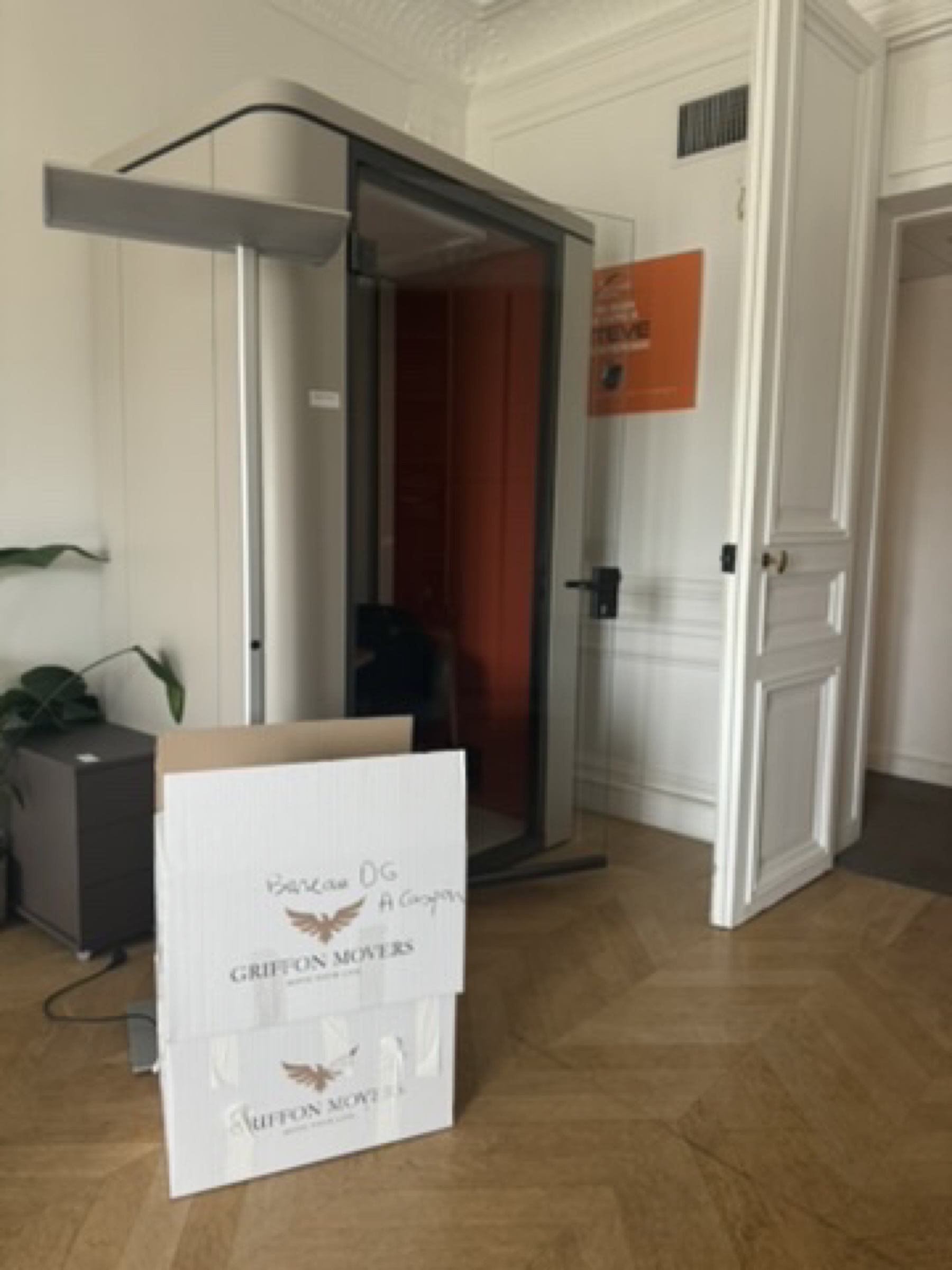 Cabine acoustique de bureau orange et noire avec cartons signés Griffon Movers, transfert d'un siège social parisien