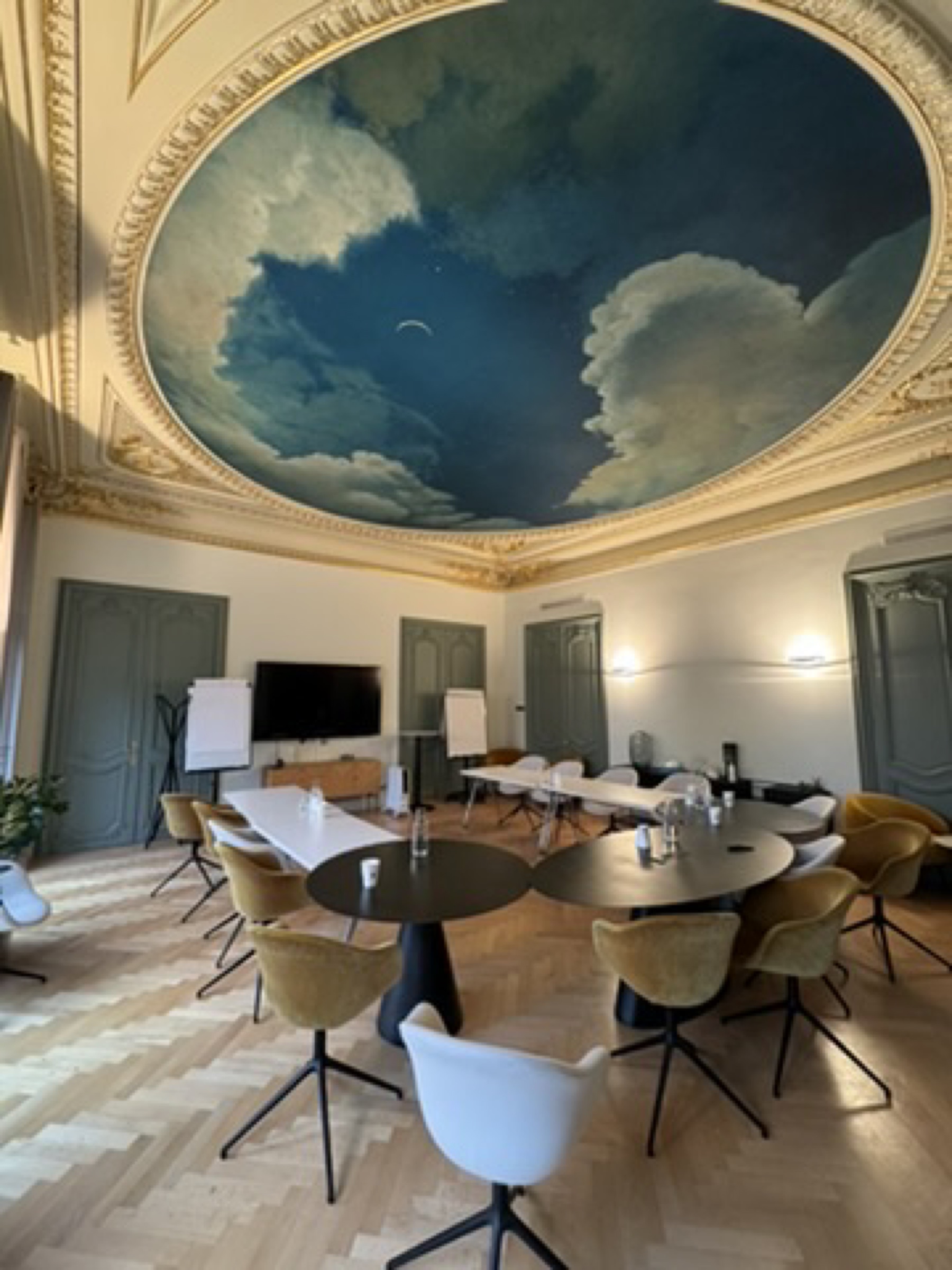 Grande salle de réception avec coupole peinte trompe-l'oeil de ciel et nuages, moulures dorées, mobilier de conférence design, transfert corporate Paris par Griffon Movers